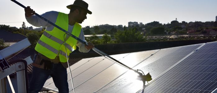 A professional solar panel cleaner on a roof