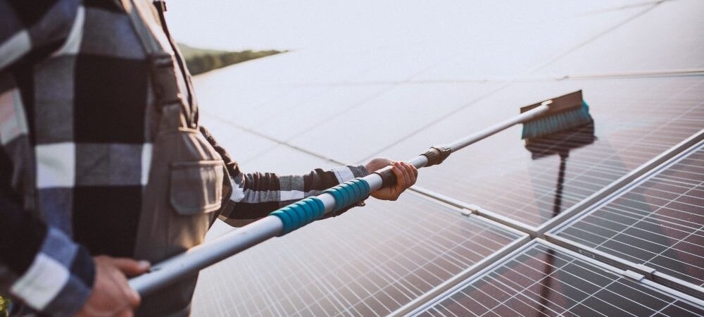 A person cleaning a solar panel system on a rooftop